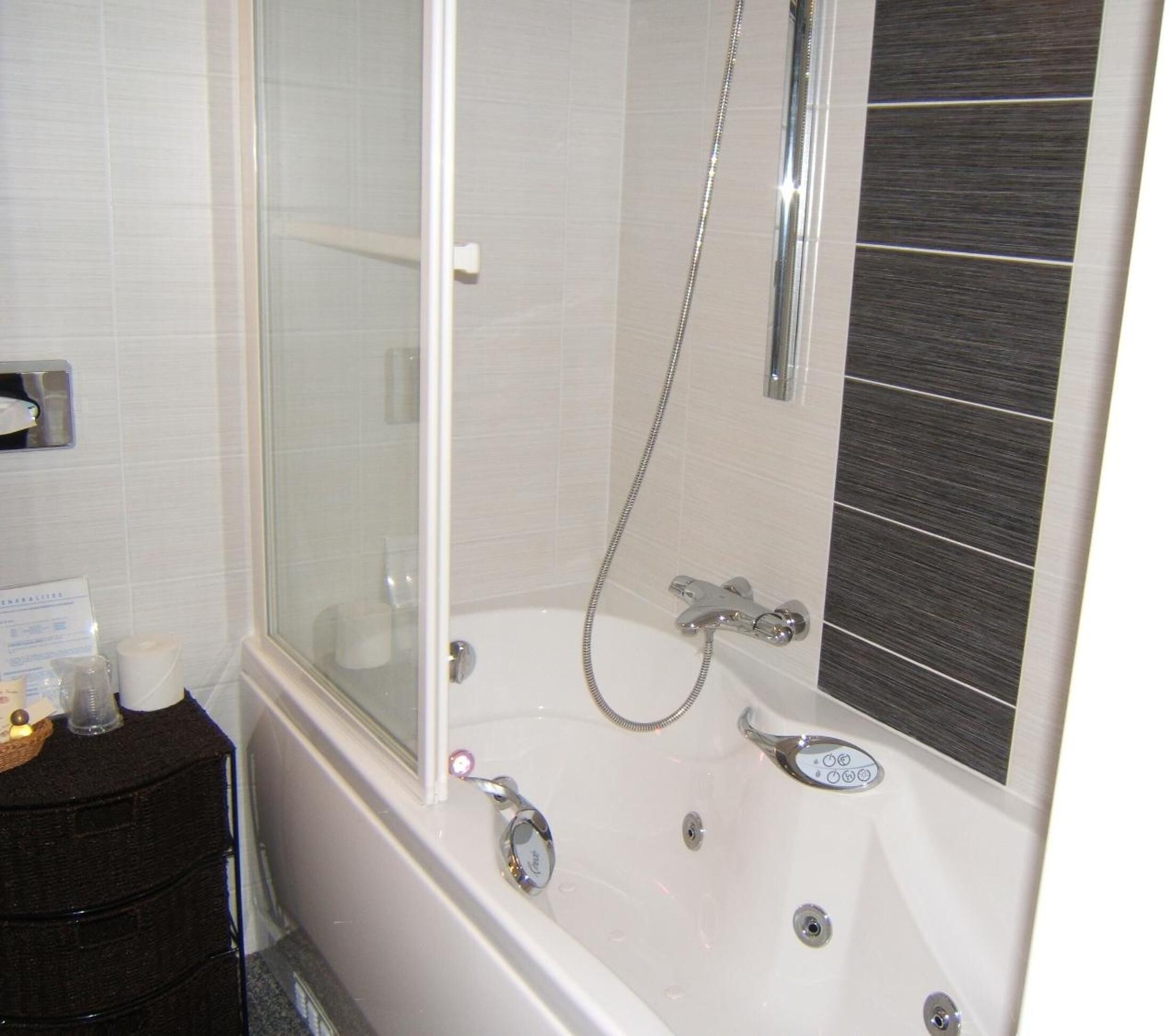 A bathroom with a bathtub, a glass shower enclosure, and a vanity with toiletries.