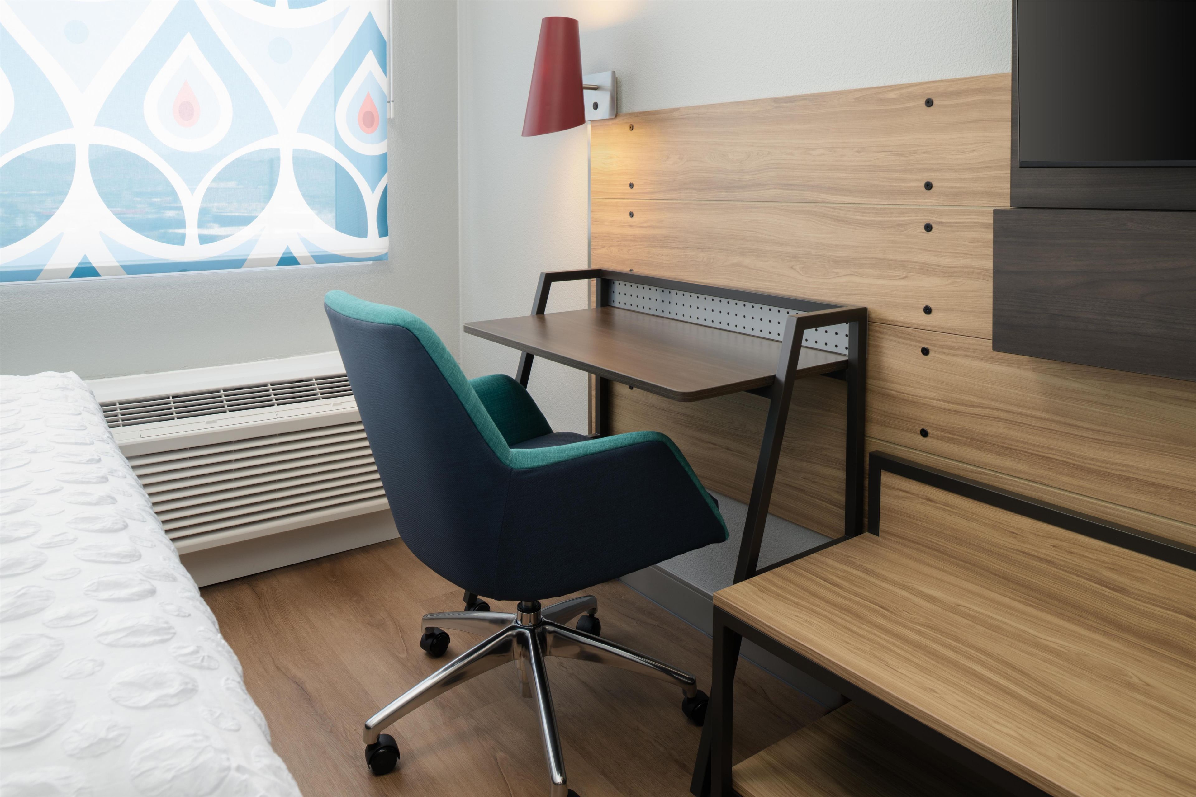 Habitación de hotel con cama, escritorio, silla, calentador y ventana con vista decorada.