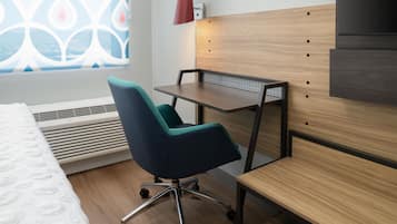 Habitación de hotel con cama, escritorio, silla, calentador y ventana con vista decorada.