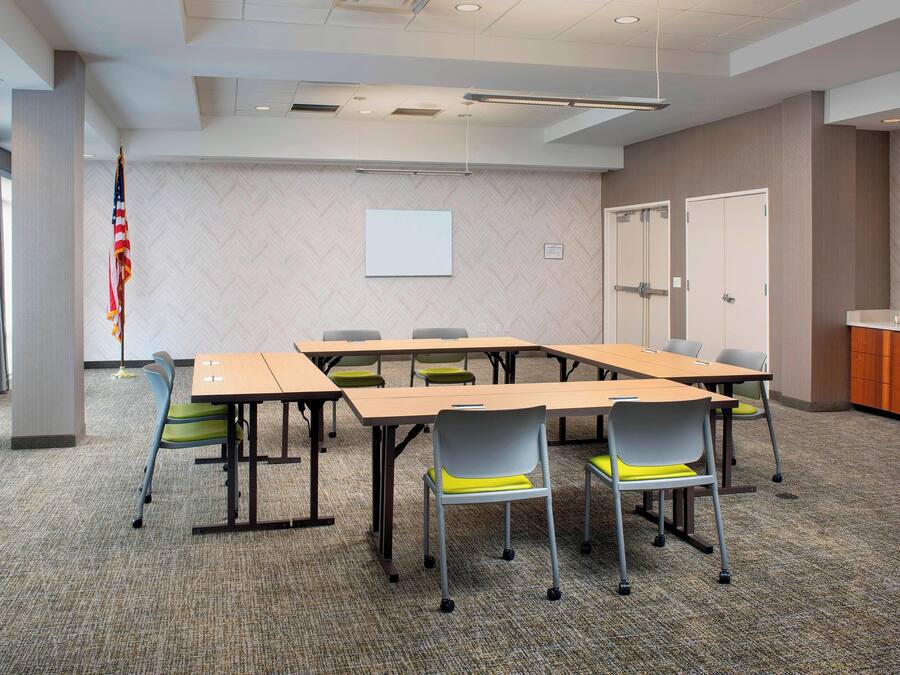 A conference room with a large table, chairs, a projector screen, and a flag.