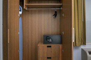 Una habitación compacta y bien organizada, con un armario de madera, un mueble pequeño y un microondas sobre una encimera de madera.
