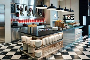 A modern kitchen with stainless steel appliances, a checkered floor, and neatly arranged glassware and plates. - citizenM Glasgow (Glasgow)