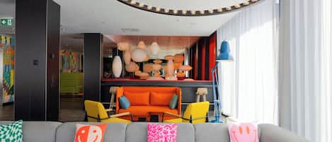 A modern lobby with a grey sofa, colorful cushions, and a vibrant interior design.
