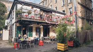 Un pub traditionnel doté d’une terrasse, d’un balcon décoré de rouge et d’une façade en briques.