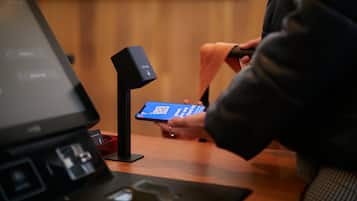 Eine Person nutzt ein Smartphone an einem Selbstbedienungsterminal mit einem QR-Code.