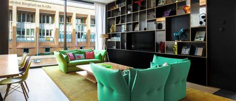 Ein modernes Wohnzimmer mit grünen Sofas, einem Holztisch und einer schwarzen Unterhaltungseinheit mit Regalen.