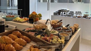 Un bufé con diversas opciones de comida, incluyendo pasteles, frutas y quesos.