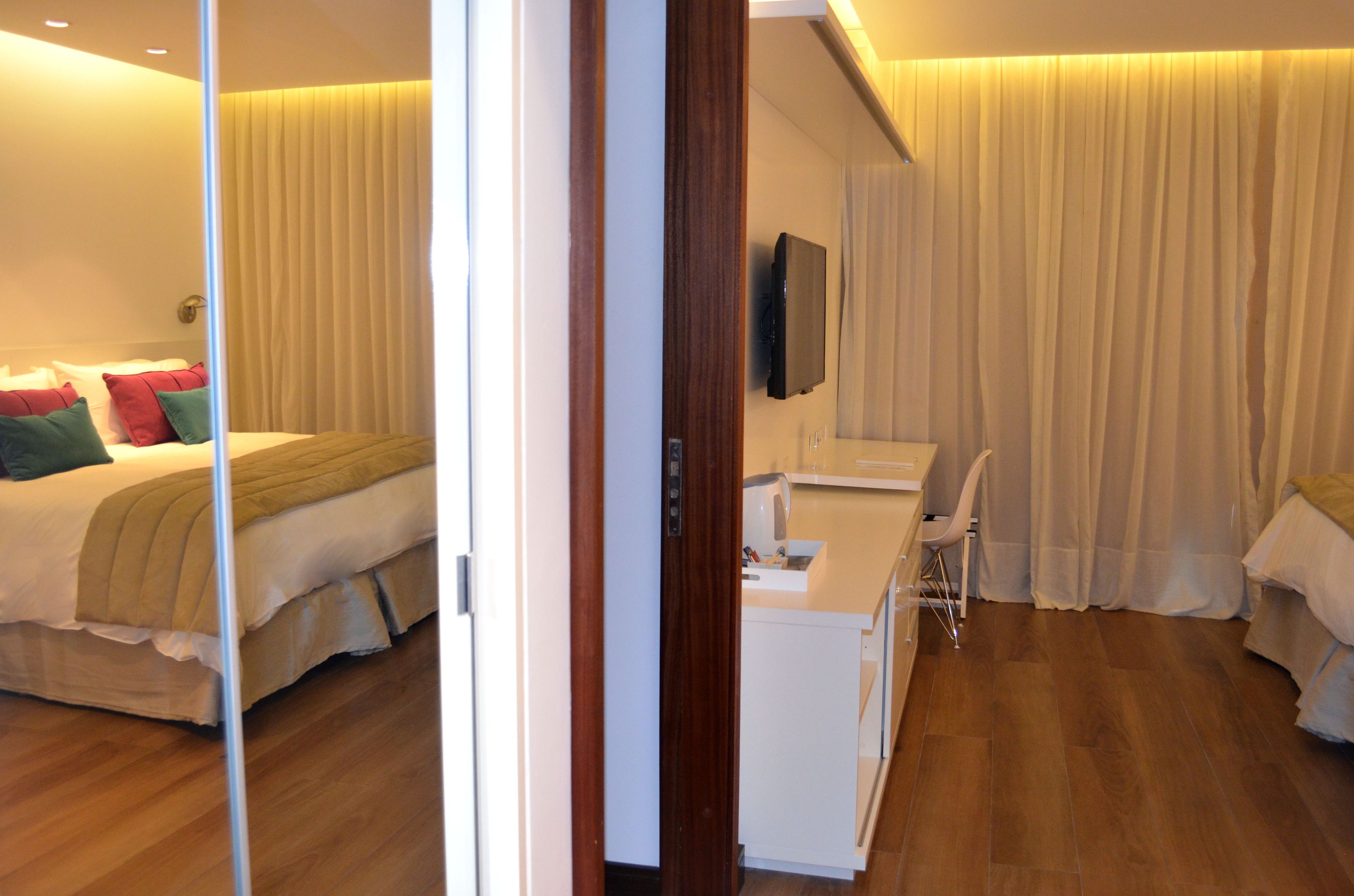 A hotel room with a bed, a desk, a chair, a TV, and a bathroom.
