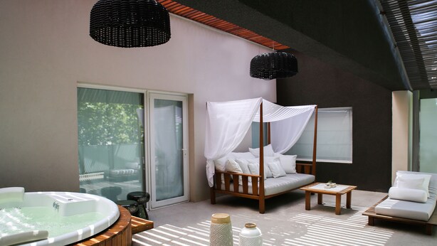 Un dormitorio moderno con una cama con dosel de madera, un jacuzzi y vistas al exterior.