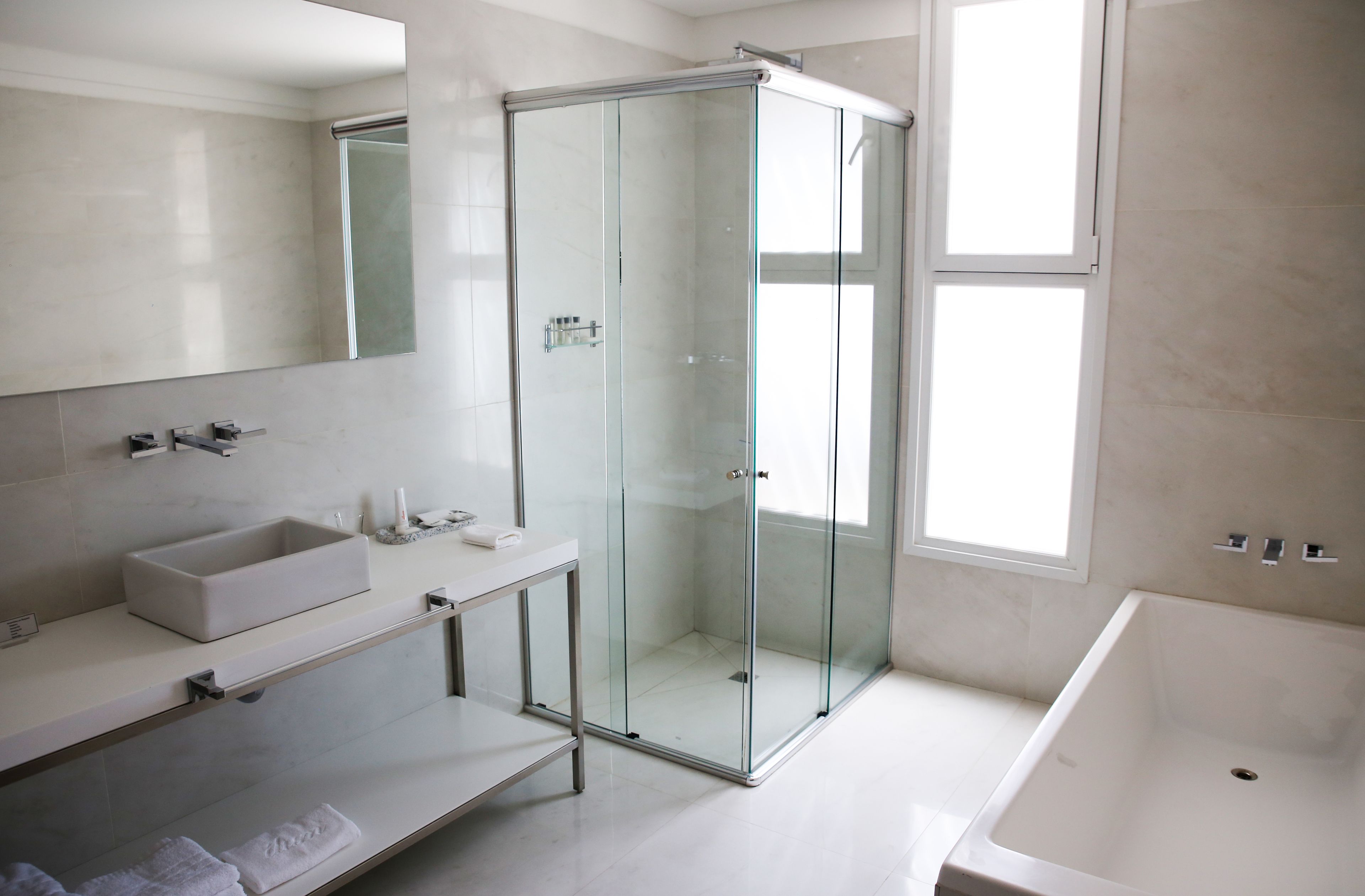 A modern bathroom with a glass-enclosed shower, a large bathtub, and a vanity with a sink and mirror.