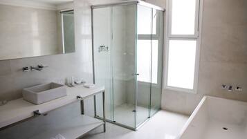 A modern bathroom with a glass-enclosed shower, a large bathtub, and a vanity with a sink and mirror.