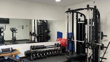 A gym with a bench press, dumbbells, a squat rack, and a mirror.