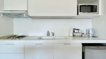A modern kitchen with white cabinetry, a microwave, a sink, and a dishwasher.