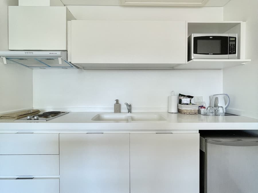 A modern kitchen with white cabinetry, a microwave, a sink, and a dishwasher.