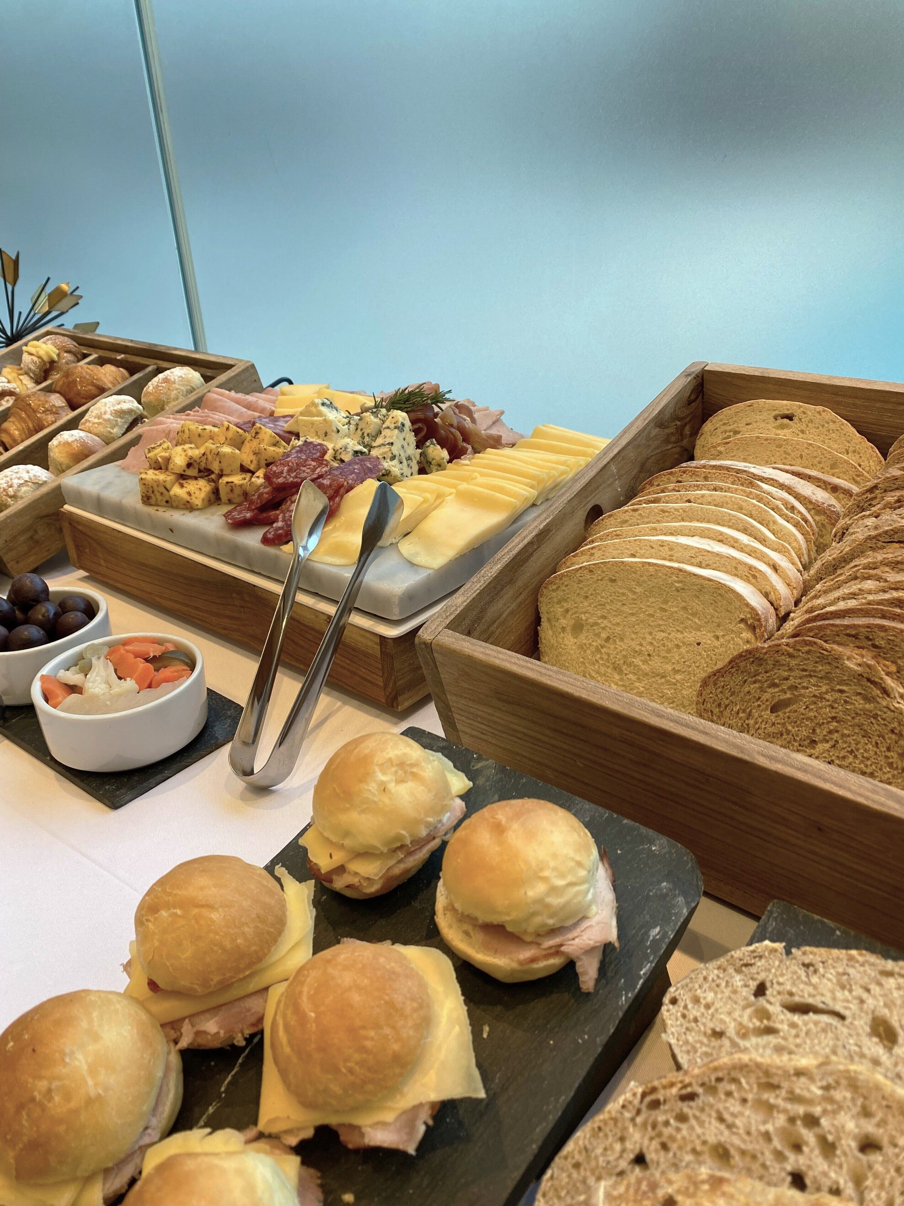 A buffet with various food items including cheese, meats, and bread.