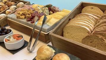 A buffet with various food items including cheese, meats, and bread.