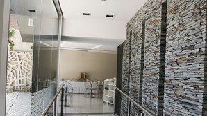 Un interior moderno con barandilla de vidrio, pared de piedra y suelo de mármol.