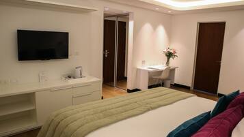 A hotel room with a bed, a desk, a chair, a television, and a mirror.