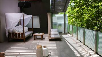 A modern outdoor lounge area with a wooden sofa, a daybed, and a small table.