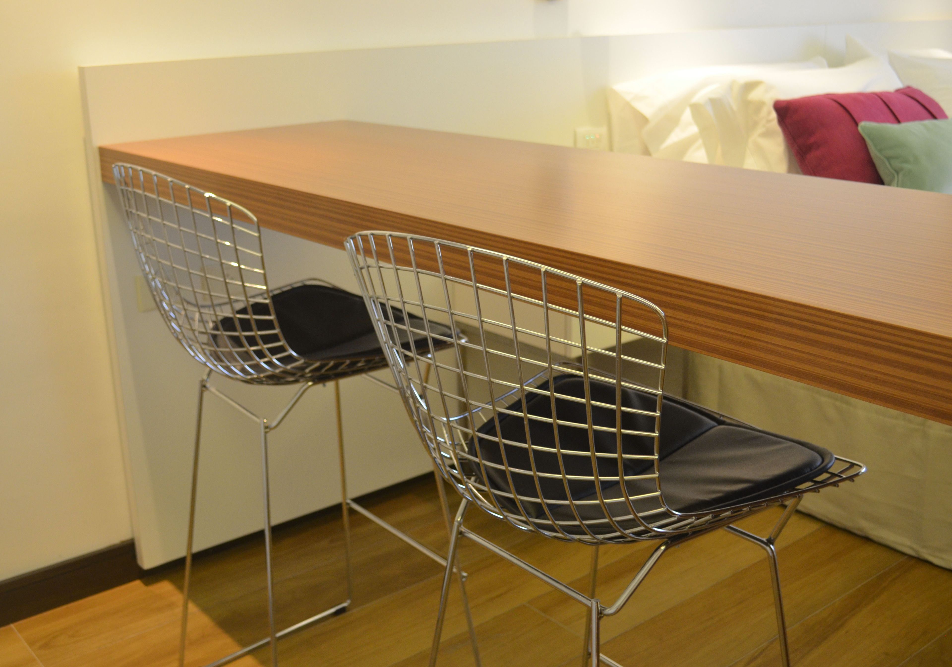 Una habitación moderna con un escritorio de madera y dos sillas de metal con cojines negros.