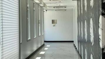 A corridor with a shiny marble floor, white walls, and a patterned wall on the right.