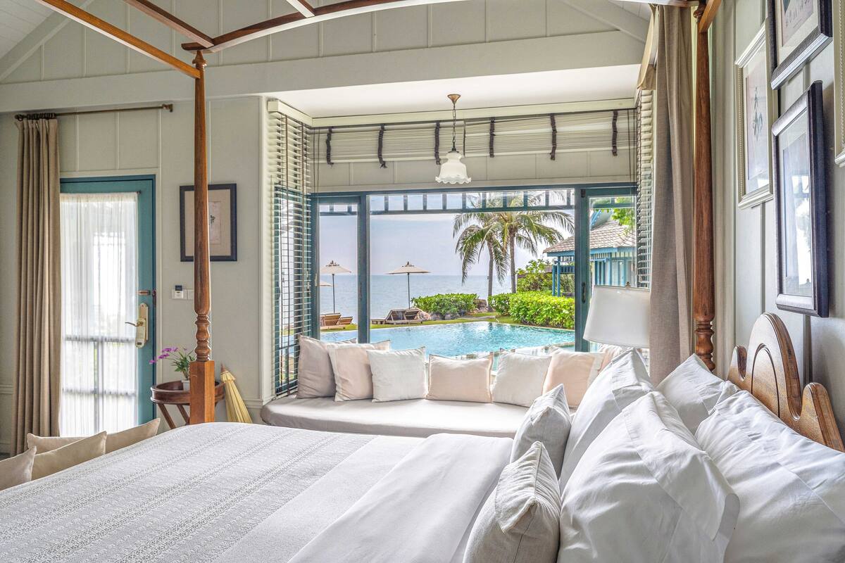 Un dormitorio con una cama grande, vistas a una piscina y un balcón con vistas al mar.