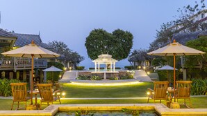 Un jardín tranquilo con un pabellón, zona de estar y un estanque cubierto de lirios.