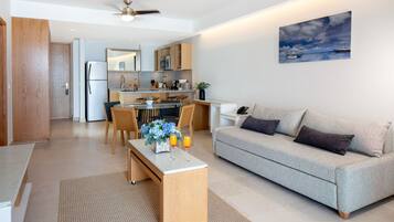 A modern living room with a grey sofa, wooden coffee table, and a dining area with a glass-top table and chairs.
