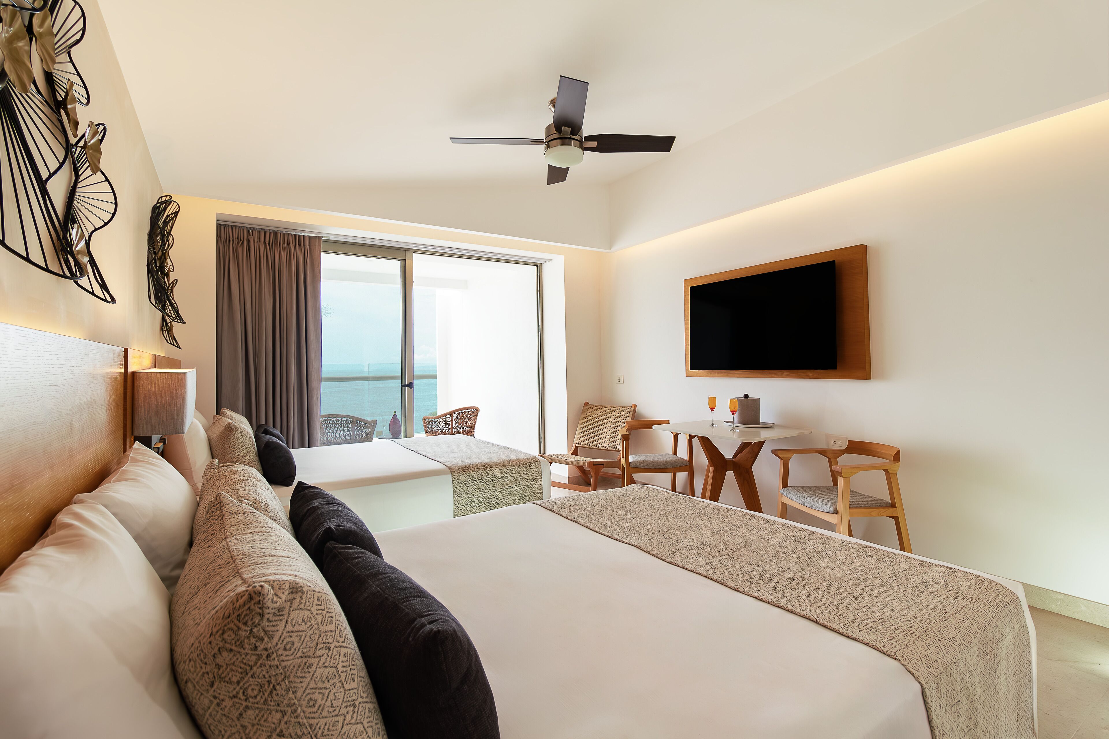 Une chambre d’hôtel avec un grand lit, un bureau, une chaise, une télévision et un balcon avec vue.
