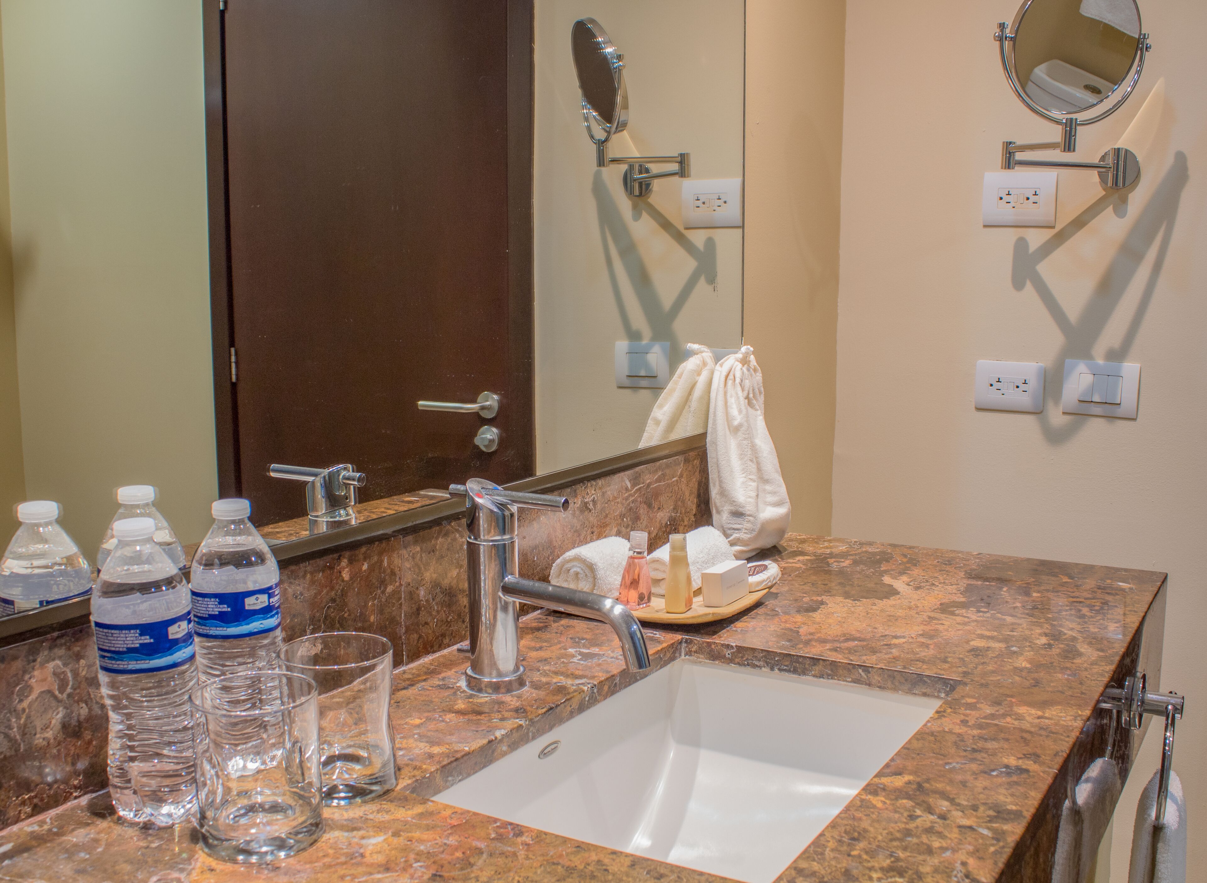A bathroom with a marble sink, a mirror, a towel, and toiletries.