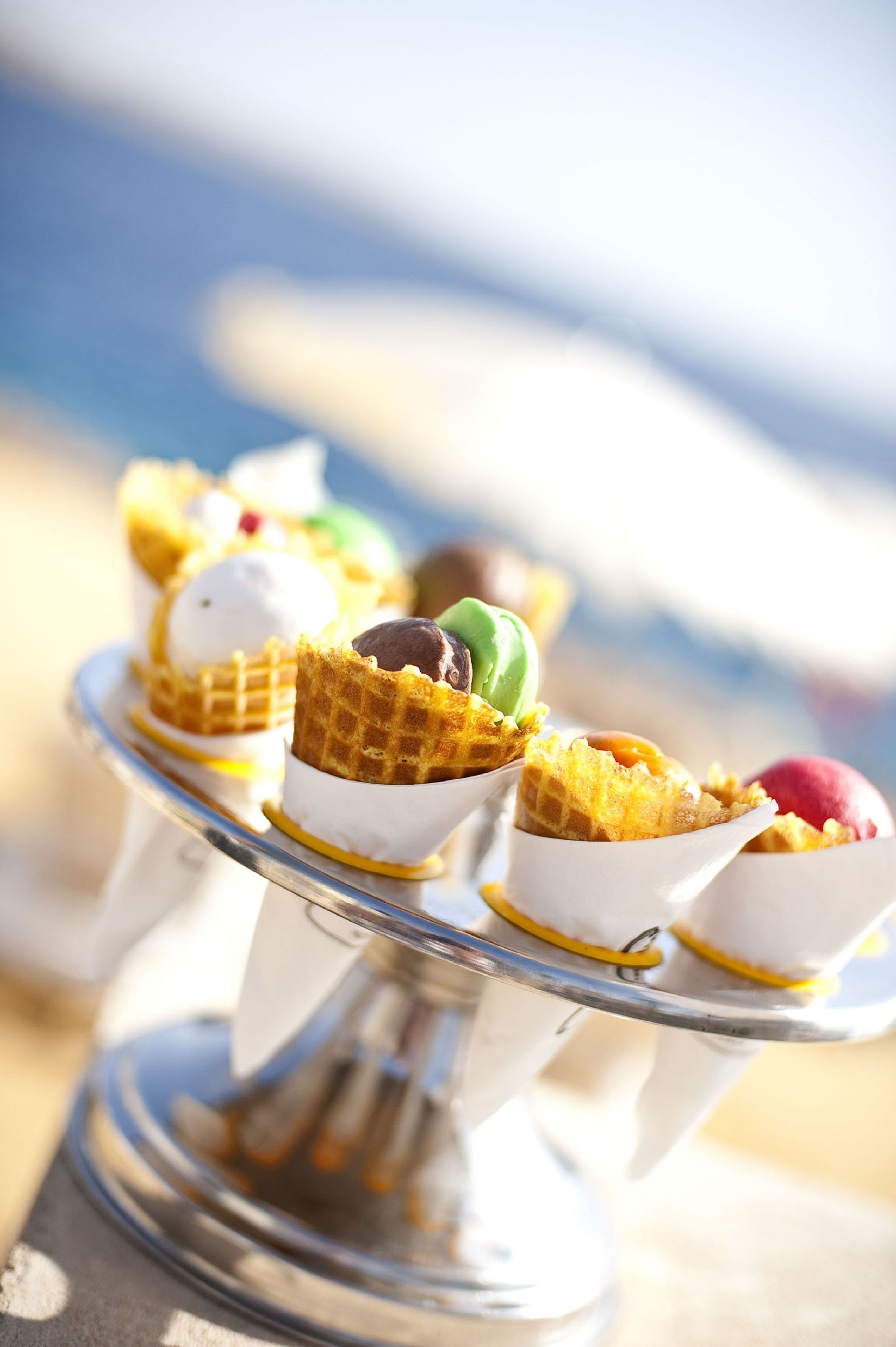 A dessert display with various ice cream cones on a silver stand.