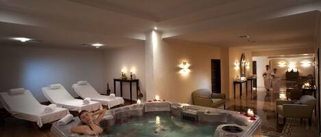A spa area with a hot tub, lounge chairs, and a massage table.