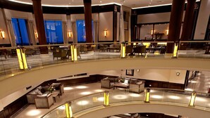 Een hotel lobby met meerdere verdiepingen, een fontein in het midden, glazen balustrades en zitgedeeltes.