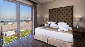 A hotel room with a large bed, a view of the airport, and a tufted headboard. - The Waterfront hotel & spa by Misty blue hotels (Durban)