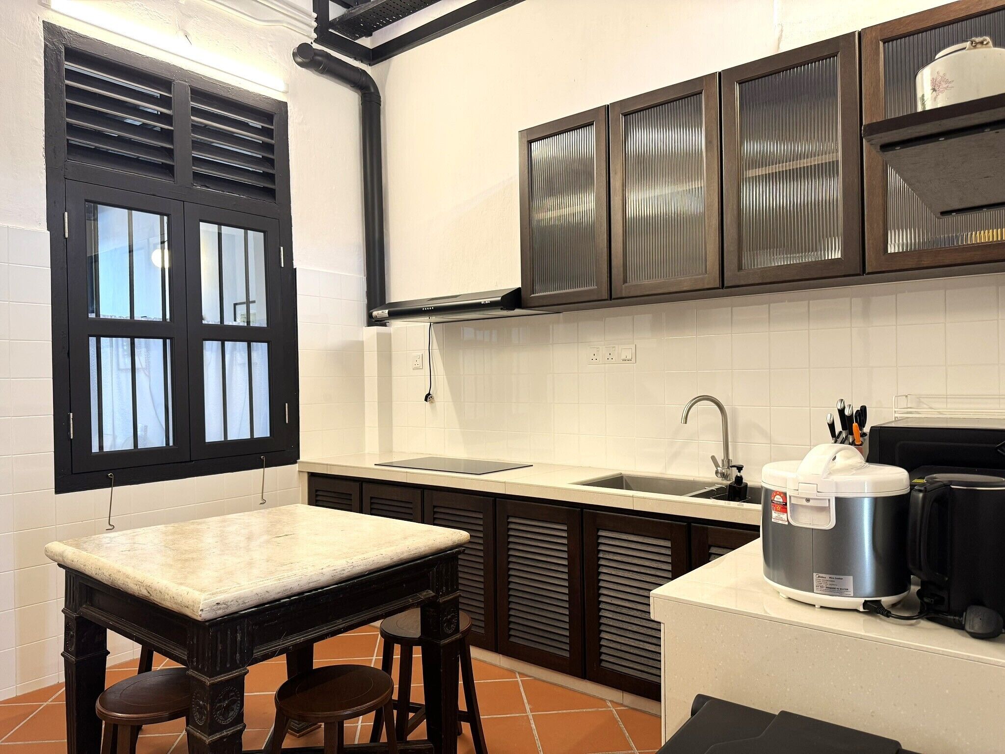 A kitchen with a window, a sink, a stove, and a coffee maker.