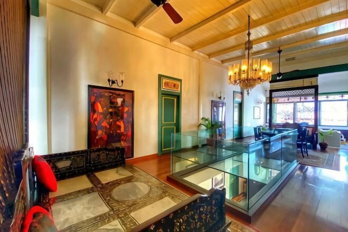 A spacious living area with a glass coffee table, a sofa, and a chandelier.