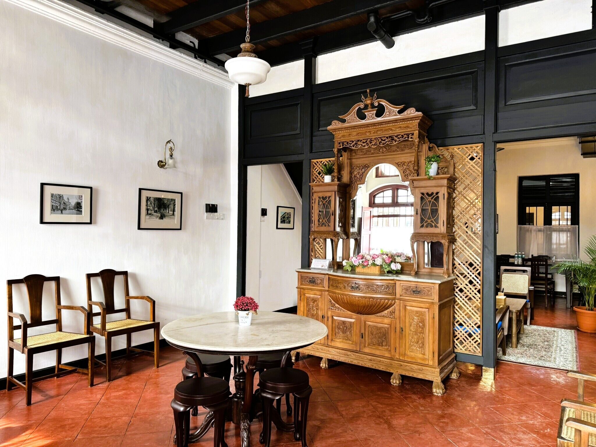 Un comedor con una mesa redonda, sillas y un aparador de madera con intrincados adornos.