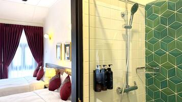 A hotel room with two beds, a shower, and a green-tiled wall.