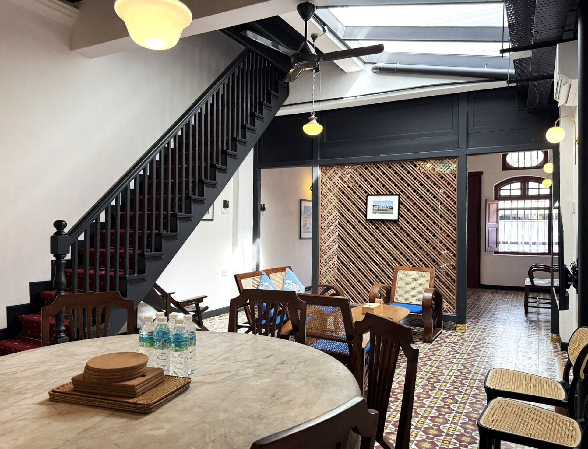 A restaurant with a high ceiling, a staircase, and a patterned wall.