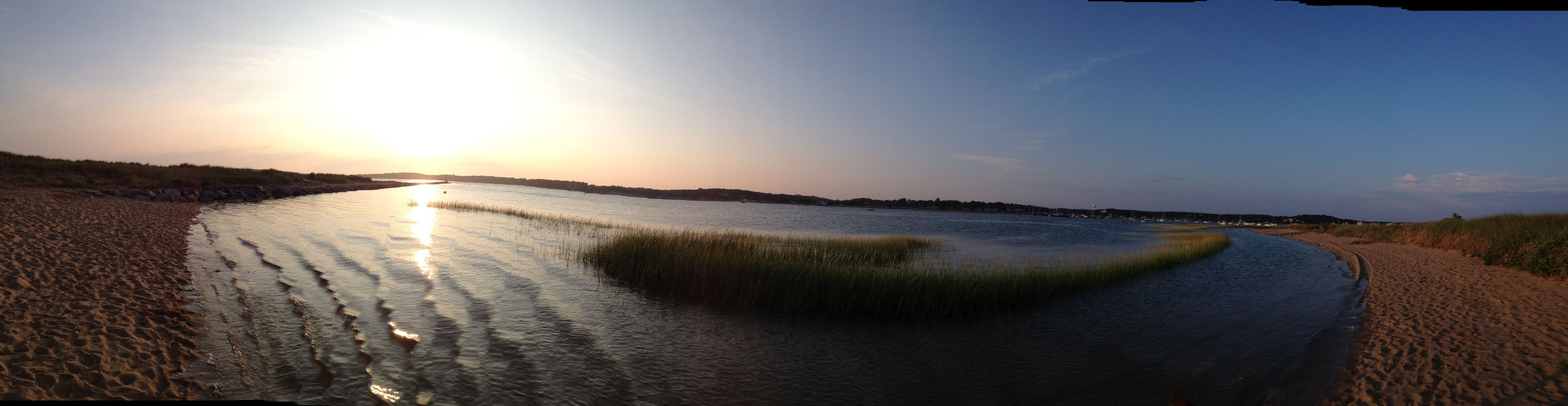 A riverbank with a sandy path and grassy areas.