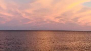 Mar calmo com horizonte nítido e céu em tons suaves de rosa e azul.
