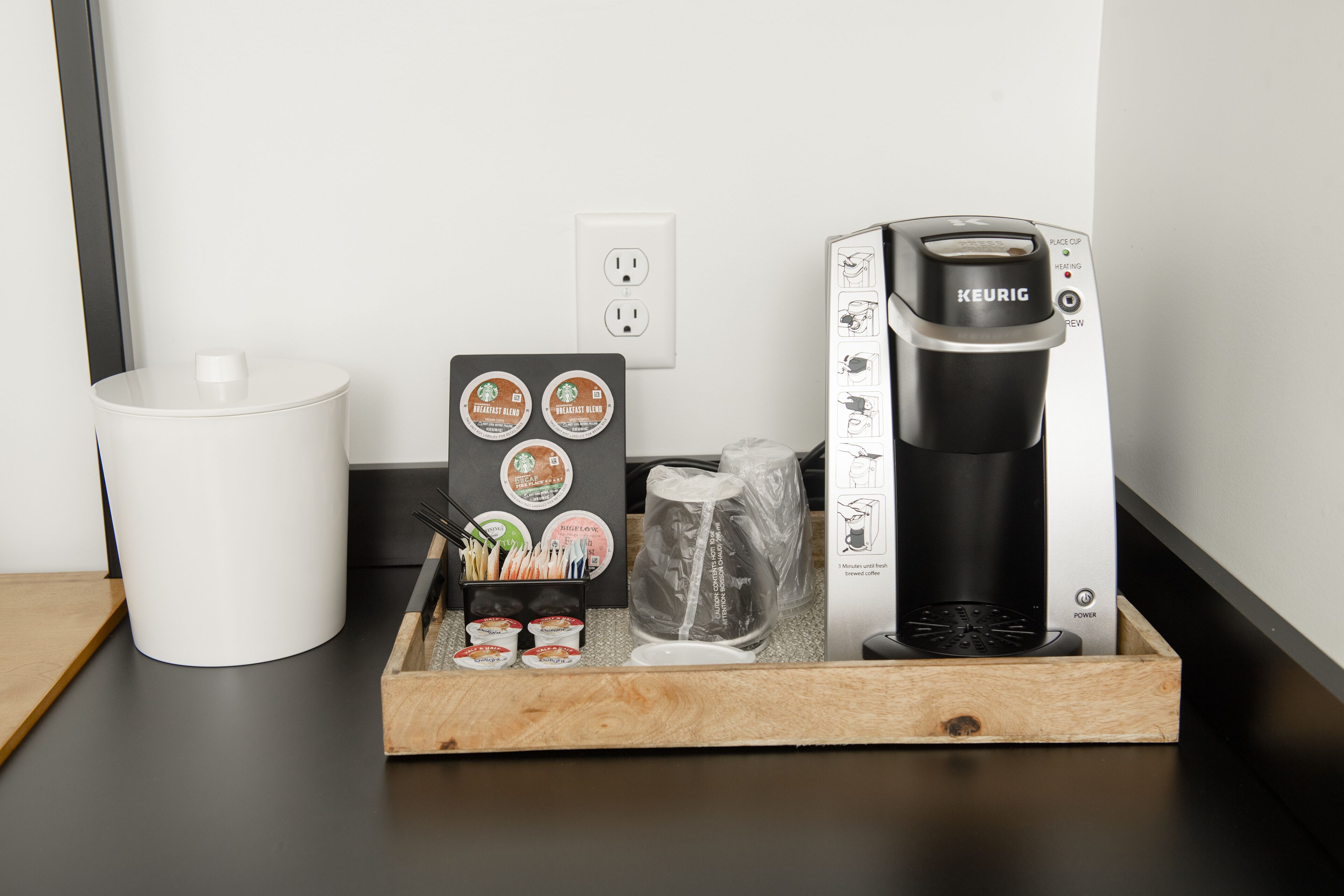 A coffee maker, a white mug, a tray with coffee cups, and a coffee pod holder on a countertop.