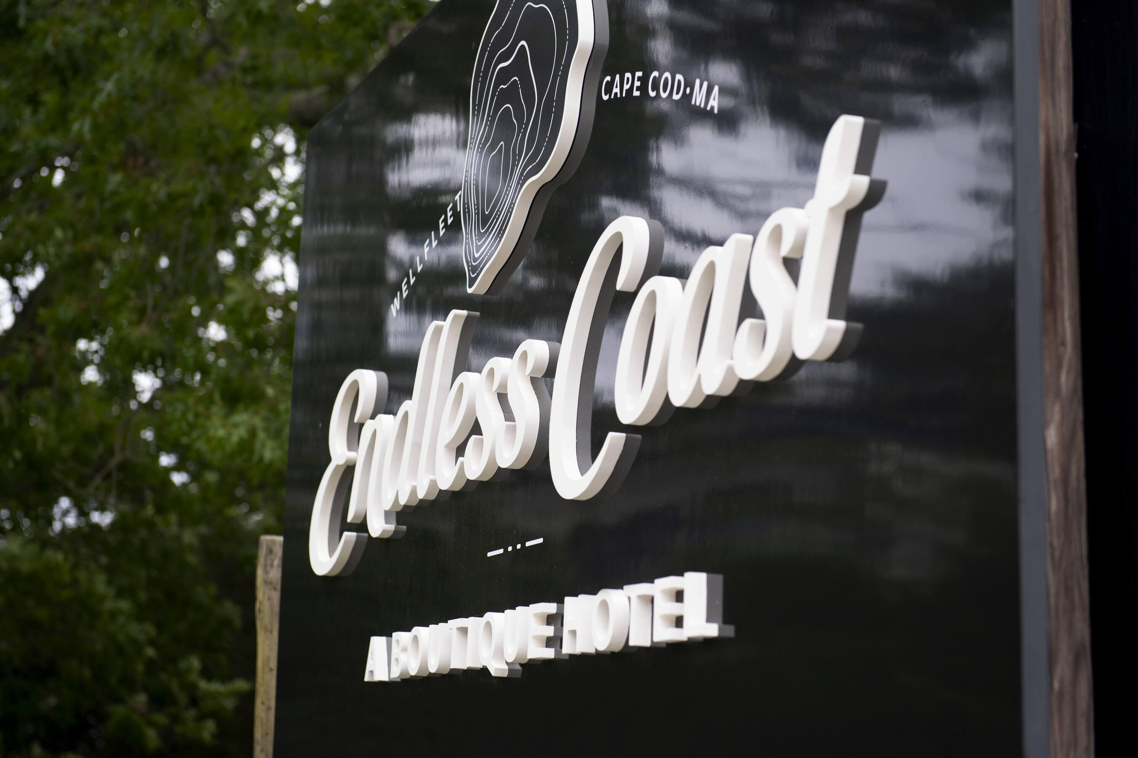 A sign for the "Endless Coast Boutique Hotel" with a stylized logo and the name in large, cursive letters.