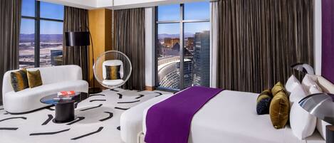 Ein modernes Hotelzimmer mit einem großen Bett, einer Couch, einem runden Sessel und Blick auf die Stadt.