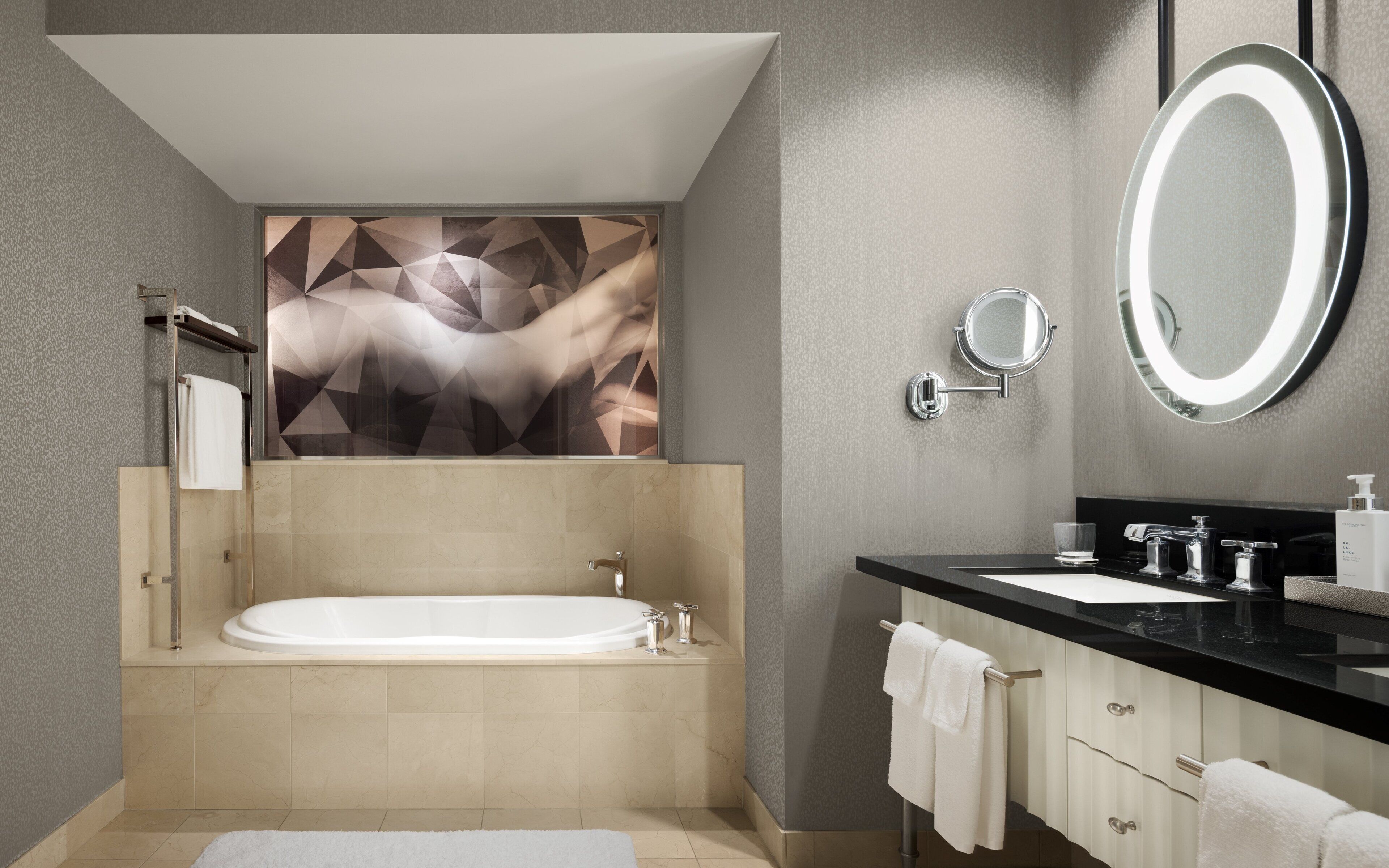 Une salle de bain moderne avec une baignoire sur pieds, un grand miroir et un plan de toilette noir avec un lavabo.