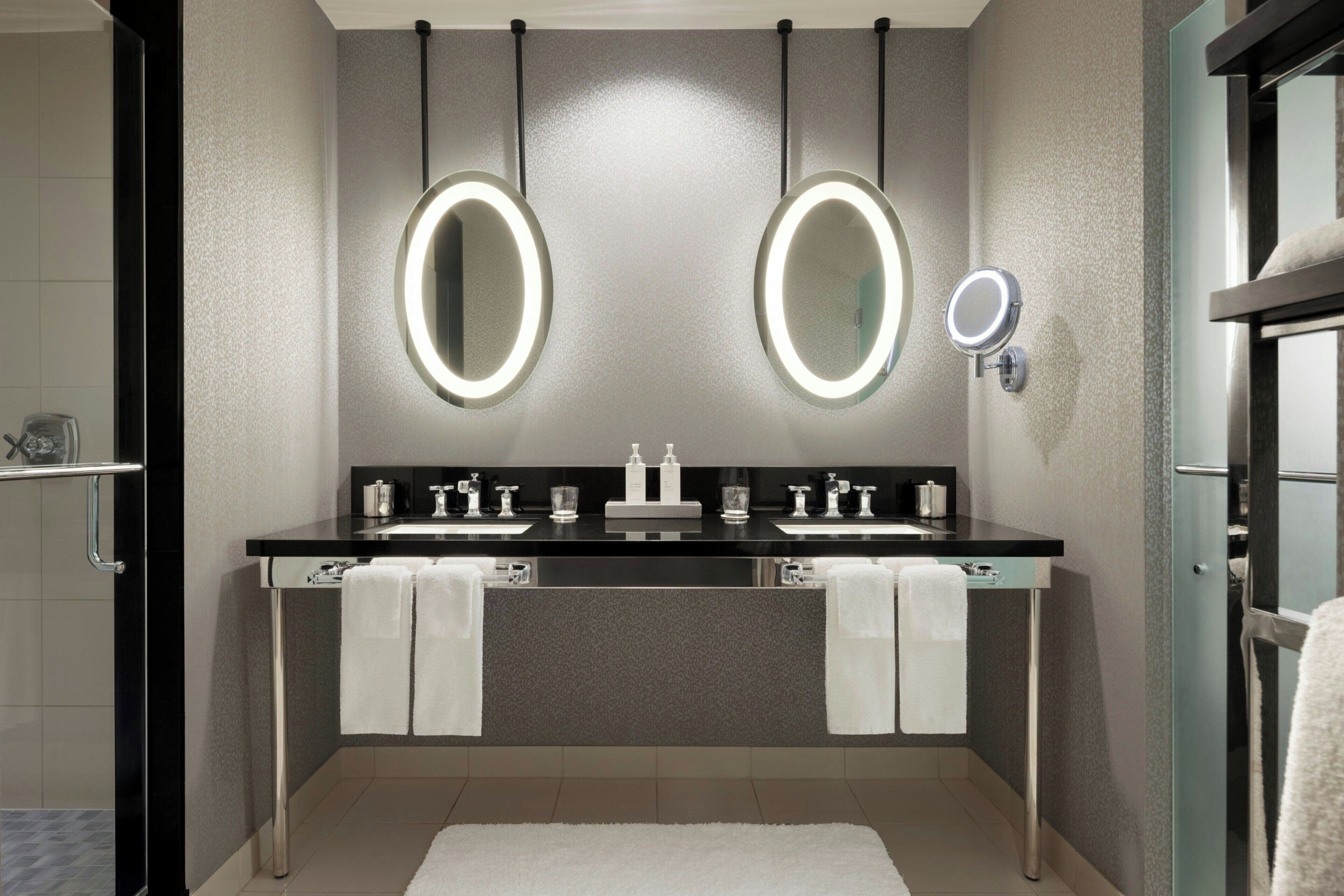 A modern bathroom with two sinks, large mirrors, and a glass shower enclosure.