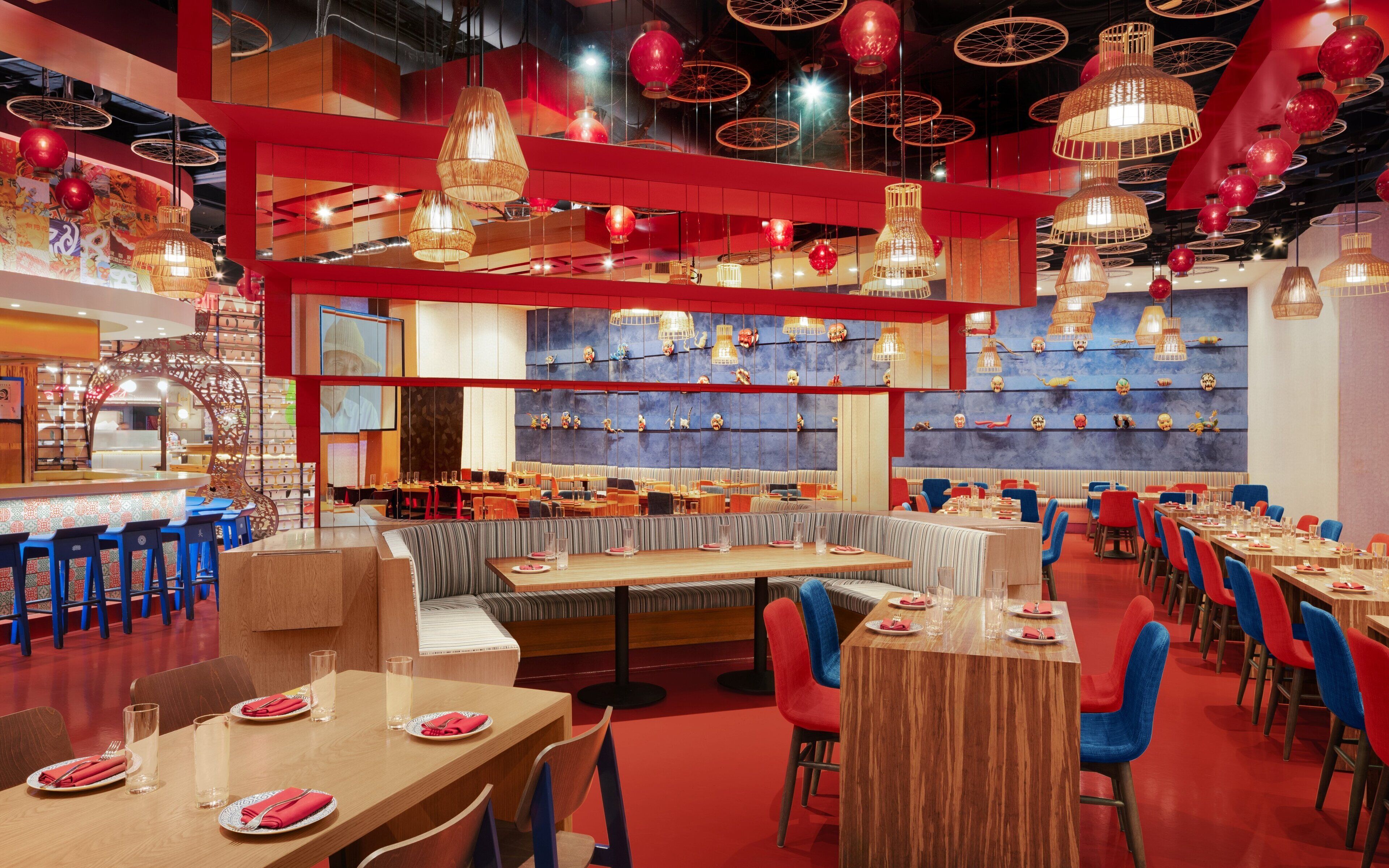 Een restaurant met verschillende eetgedeeltes, waaronder zitjes en tafels, plus een bar met krukjes.