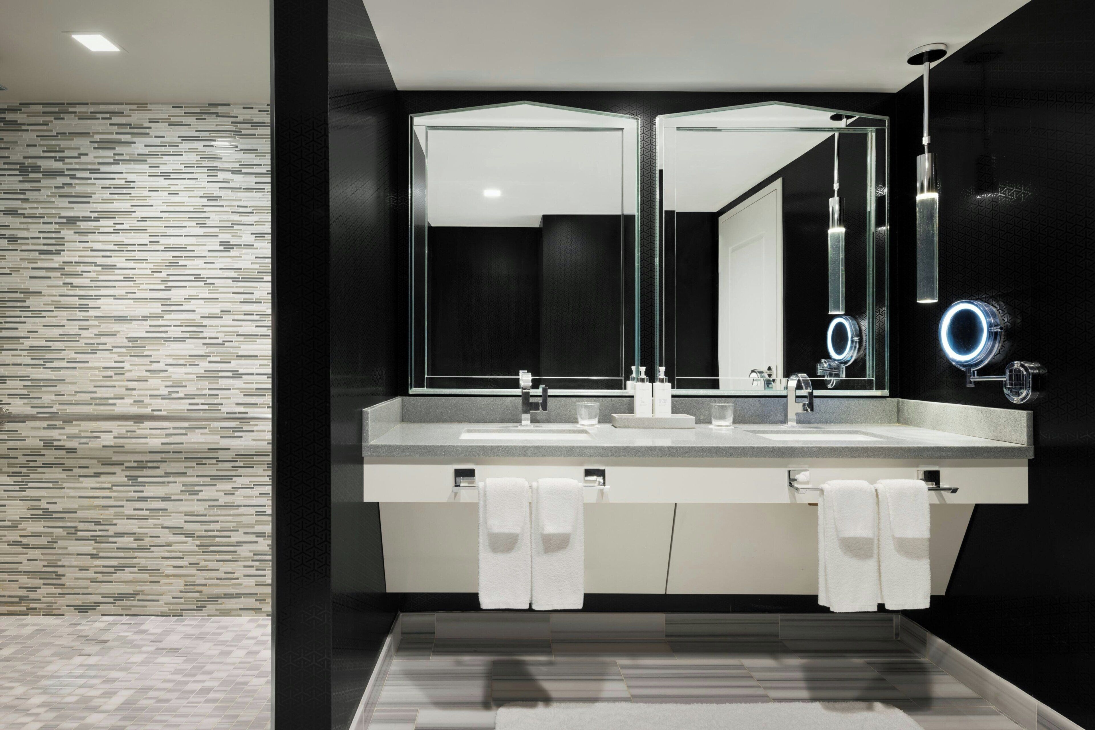 Ein modernes Badezimmer mit zwei Waschbecken, großen Spiegeln und Fliesenboden.