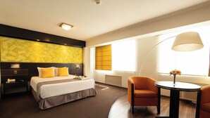 A hotel room with a bed, bedside tables, a desk, a chair, a lamp, and a window with blinds. - Britania Miraflores (Lima)