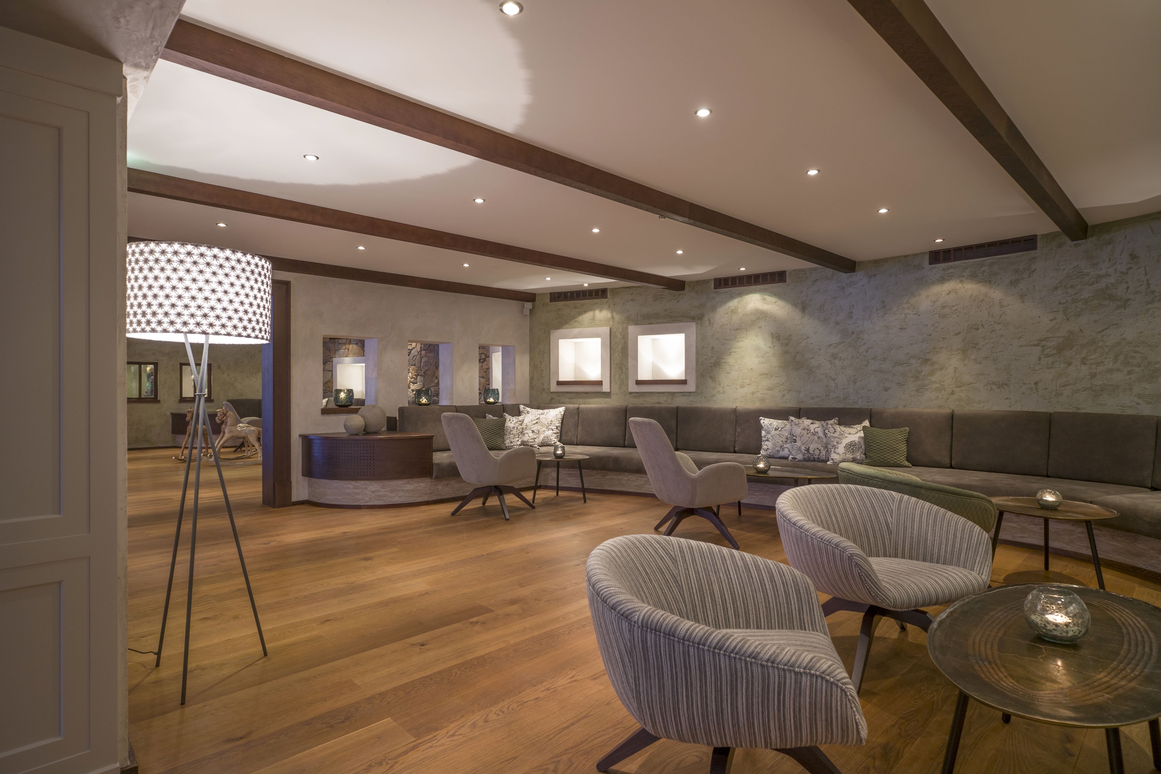 A spacious living area with a wooden floor, a stone accent wall, and modern furniture including a sofa, chairs, and a coffee table.